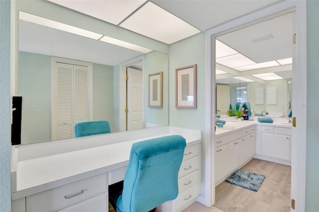 home office with sink, light hardwood / wood-style floors, and built in desk