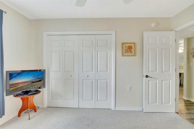 carpeted bedroom with ceiling fan and a closet