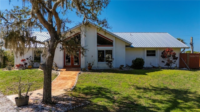 view of front of home with a front yard, french doors, metal roof, and stucco siding