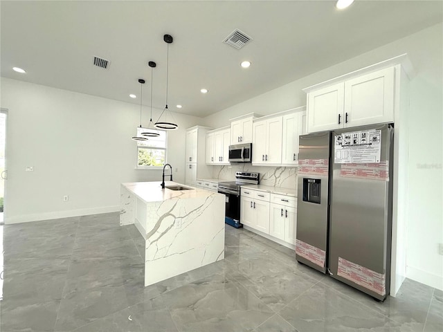 kitchen featuring appliances with stainless steel finishes, white cabinetry, hanging light fixtures, light stone counters, and a center island with sink