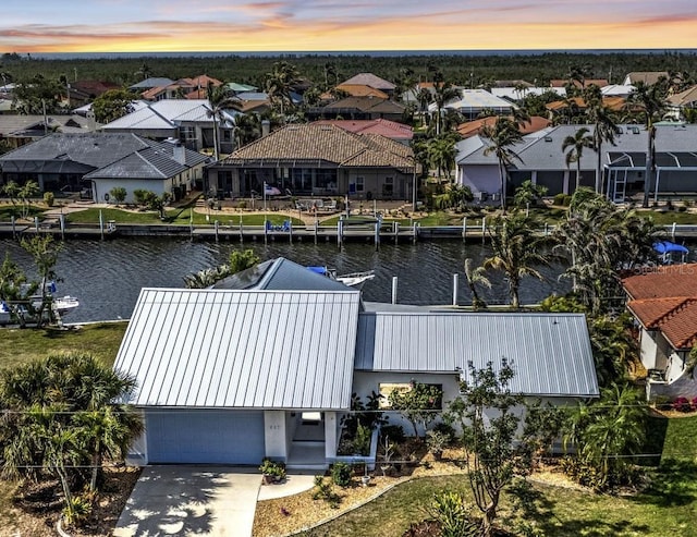 aerial view at dusk featuring a water view