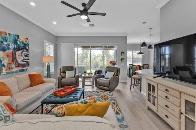 living room with light wood-type flooring, crown molding, and ceiling fan