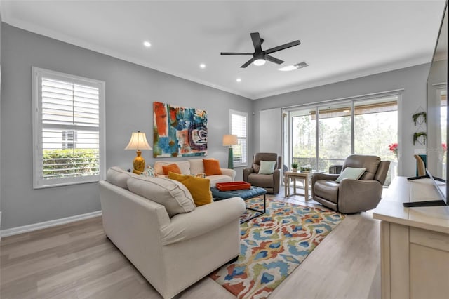 living room with light hardwood / wood-style flooring, a wealth of natural light, ceiling fan, and ornamental molding