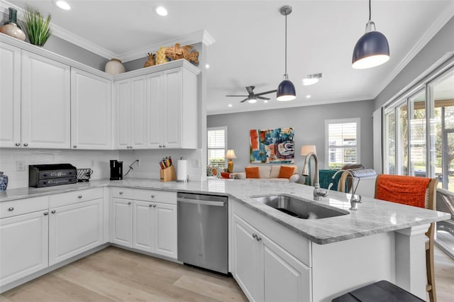 kitchen with hanging light fixtures, stainless steel dishwasher, crown molding, sink, and white cabinetry