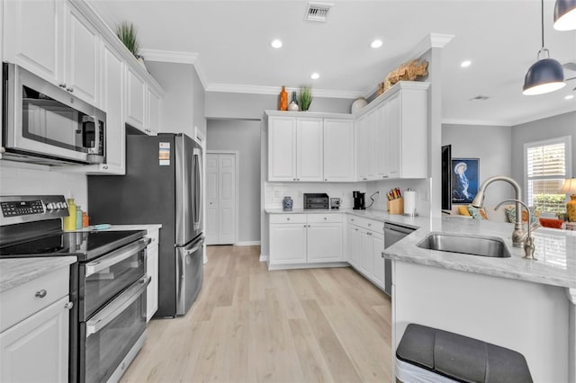 kitchen with hanging light fixtures, appliances with stainless steel finishes, white cabinetry, and sink