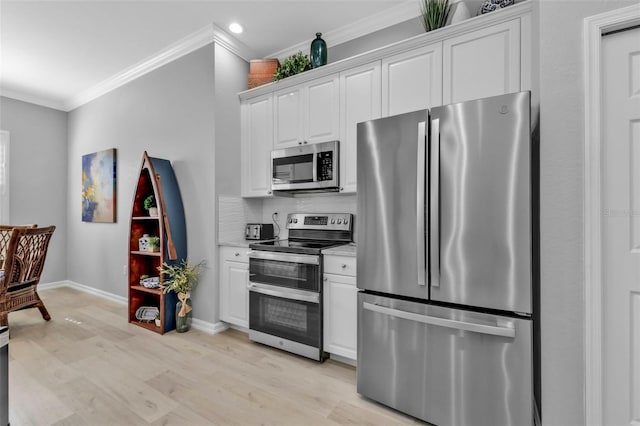 kitchen featuring white cabinets, light wood-type flooring, appliances with stainless steel finishes, and ornamental molding