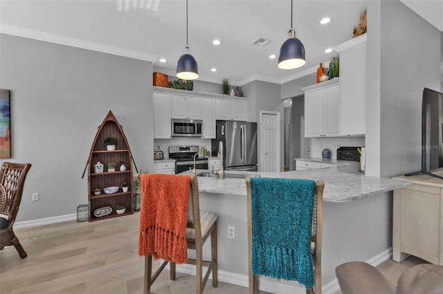 kitchen featuring appliances with stainless steel finishes, a kitchen breakfast bar, decorative light fixtures, white cabinetry, and kitchen peninsula