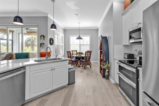 kitchen with sink, stainless steel appliances, hanging light fixtures, and white cabinets