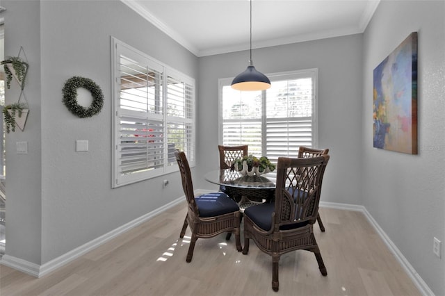 dining area with light wood-type flooring, a wealth of natural light, and crown molding