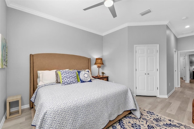 bedroom featuring light wood-type flooring, ornamental molding, ceiling fan, and a closet