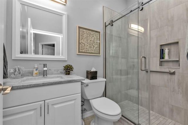 bathroom featuring vanity, toilet, and a shower with shower door