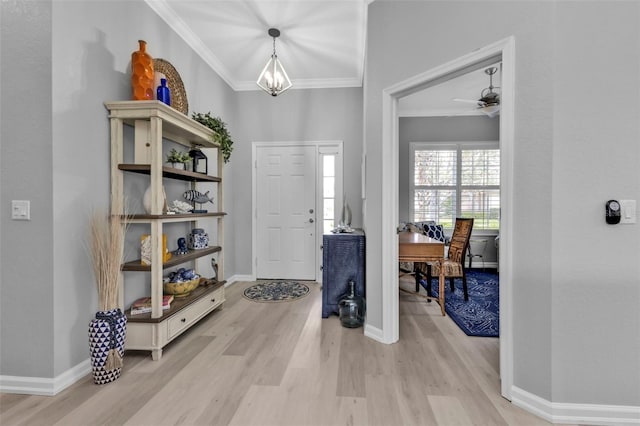 entryway with light hardwood / wood-style floors, crown molding, and an inviting chandelier