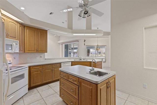 kitchen with pendant lighting, an island with sink, sink, decorative backsplash, and white appliances