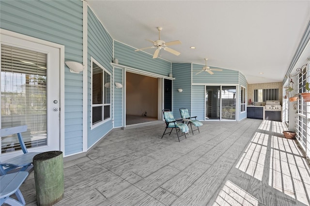 wooden terrace with ceiling fan, a grill, and exterior kitchen