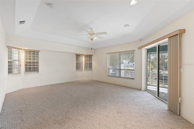 carpeted spare room featuring a raised ceiling and ceiling fan