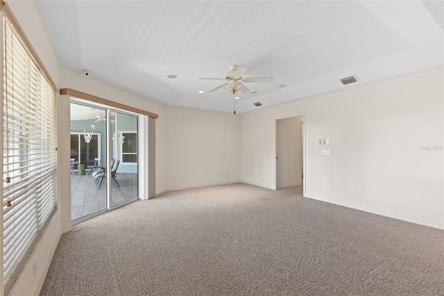 carpeted spare room with ceiling fan and a tray ceiling