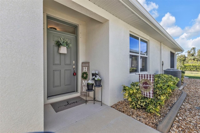 entrance to property featuring stucco siding and central air condition unit