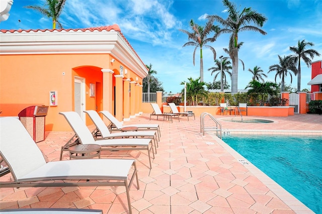 view of swimming pool featuring a hot tub and a patio area