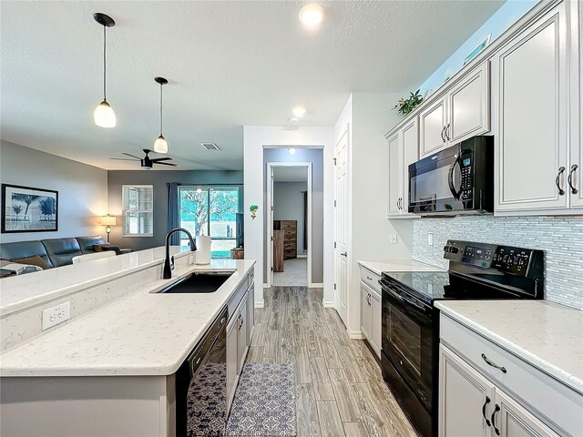 8858 Tuscany Isles Dr, Punta Gorda, FL 33950 - kitchen featuring sink, black appliances, hanging light fixtures, light stone countertops, and backsplash