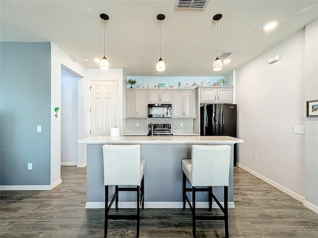 8858 Tuscany Isles Dr, Punta Gorda, FL 33950 - kitchen with a breakfast bar area, a kitchen island with sink, backsplash, black appliances, and decorative light fixtures