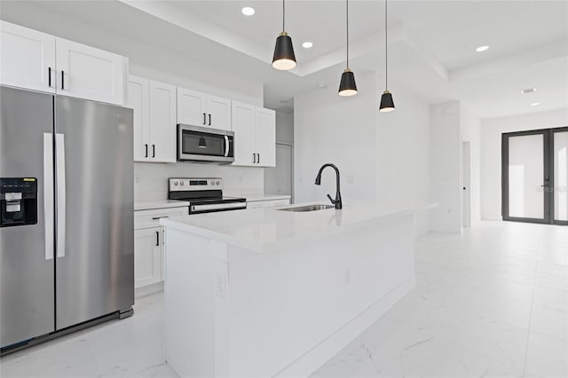 kitchen with appliances with stainless steel finishes, a kitchen island with sink, sink, and hanging light fixtures