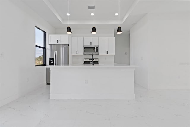 kitchen with pendant lighting, stainless steel appliances, a center island with sink, and white cabinets