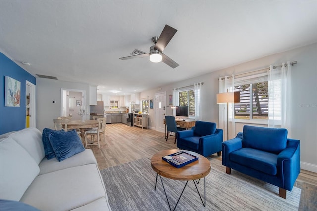 living room featuring ceiling fan and light hardwood / wood-style flooring