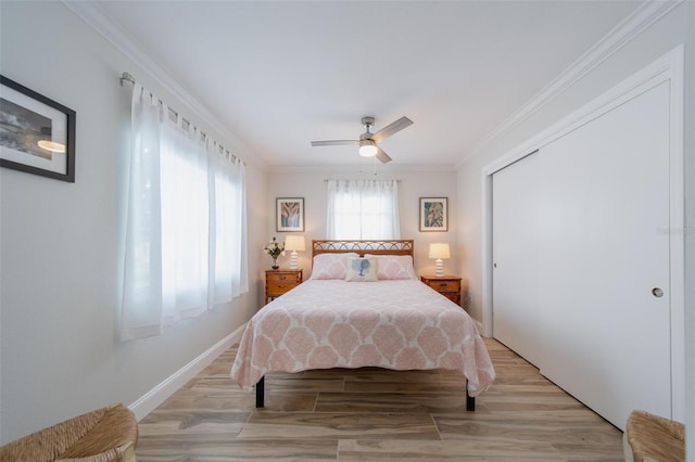 bedroom featuring ceiling fan, light hardwood / wood-style flooring, crown molding, and a closet