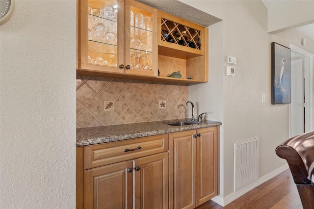 bar featuring stone countertops, sink, dark hardwood / wood-style flooring, and decorative backsplash