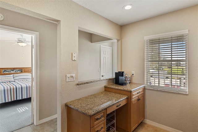 kitchen featuring light stone counters, ceiling fan, and light tile patterned floors