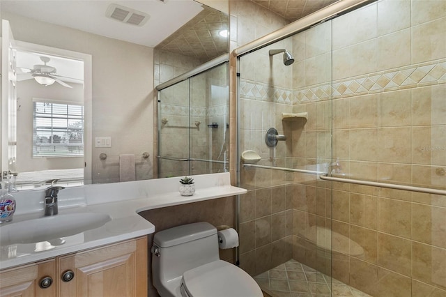 bathroom featuring ceiling fan, vanity, toilet, and a shower with shower door