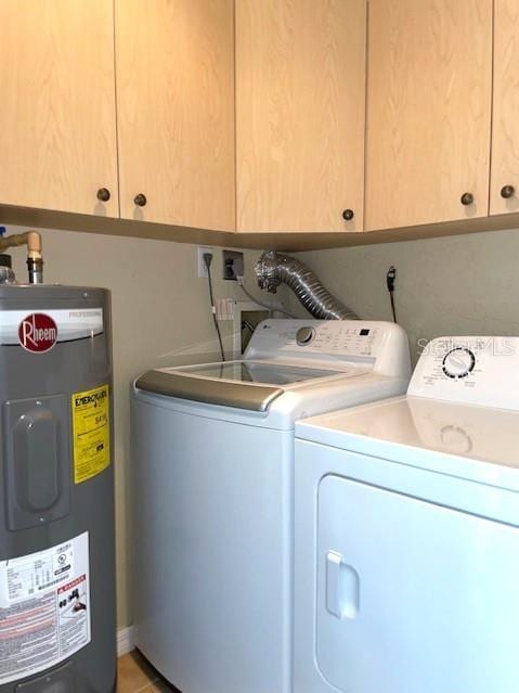 laundry area with water heater, washing machine and dryer, light tile patterned flooring, and cabinets