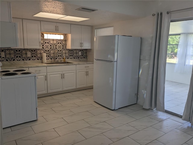 710 Aqui Esta Dr, Punta Gorda, FL 33950 - kitchen with tasteful backsplash, sink, white cabinets, and white appliances
