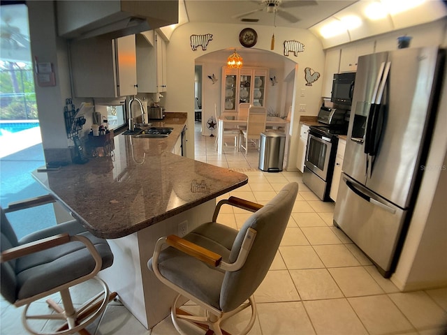 kitchen with light tile patterned flooring, sink, a kitchen breakfast bar, dark stone counters, and stainless steel appliances