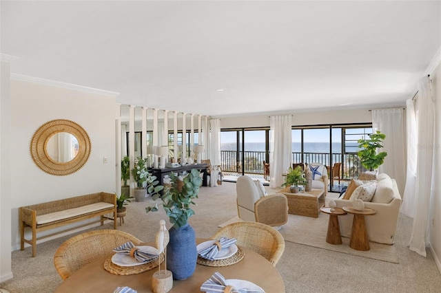 dining space with a water view, crown molding, and light colored carpet