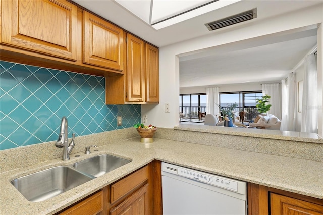 kitchen with decorative backsplash, dishwasher, light stone countertops, and sink