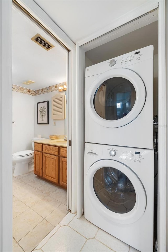 clothes washing area featuring stacked washer and dryer and light tile patterned floors