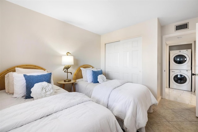 bedroom featuring stacked washing maching and dryer and a closet