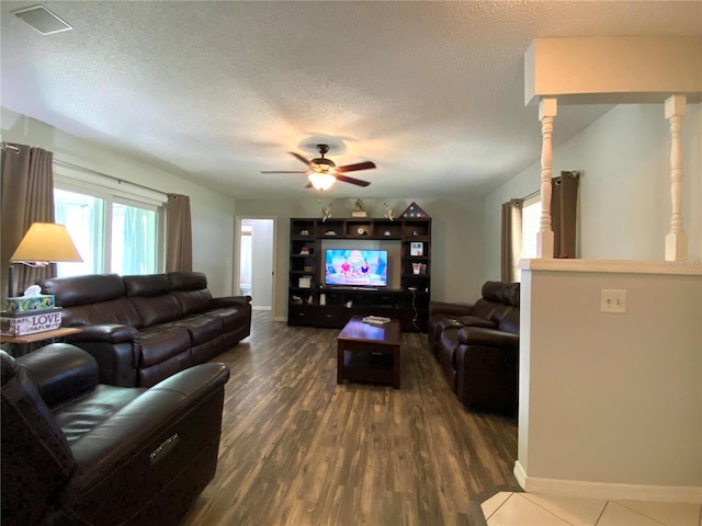 living room with dark hardwood / wood-style flooring, ceiling fan, and a textured ceiling