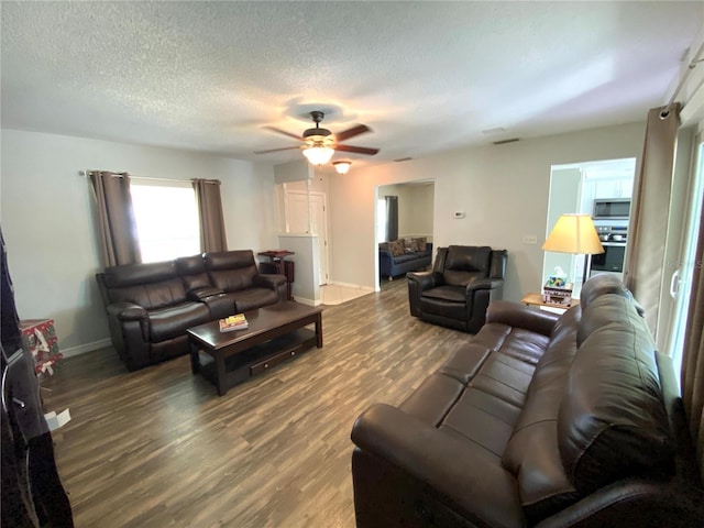 living room featuring ceiling fan, dark hardwood / wood-style floors, and a textured ceiling
