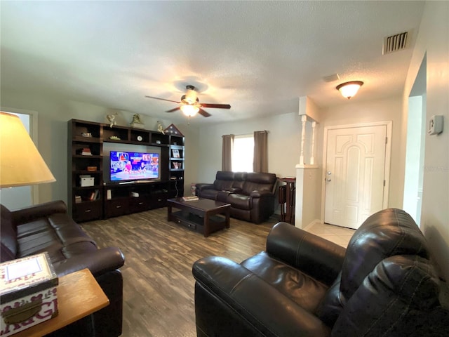 living room featuring ceiling fan, wood-type flooring, and a textured ceiling
