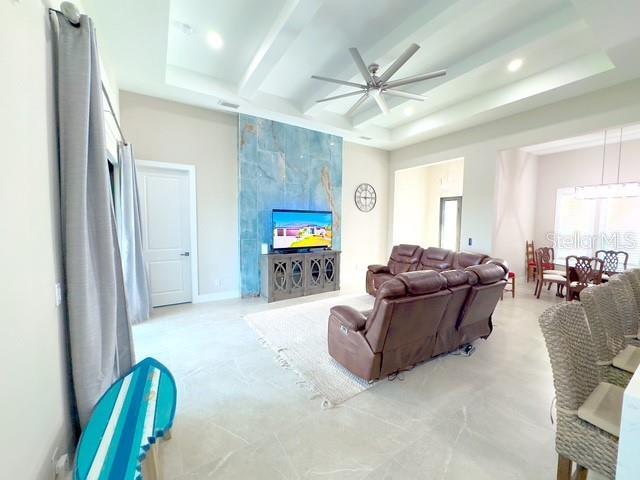 living area featuring ceiling fan, a raised ceiling, beam ceiling, and recessed lighting