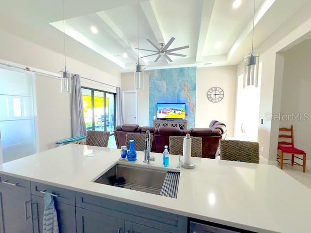 kitchen featuring a sink, open floor plan, light countertops, hanging light fixtures, and beam ceiling