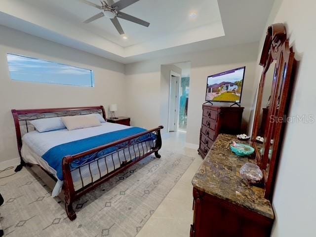 bedroom featuring a ceiling fan, a raised ceiling, and baseboards