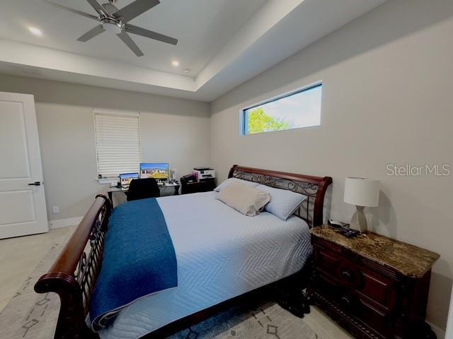 bedroom featuring baseboards, a raised ceiling, a ceiling fan, and recessed lighting