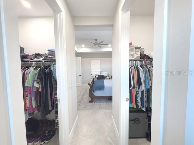 walk in closet with a tray ceiling and ceiling fan