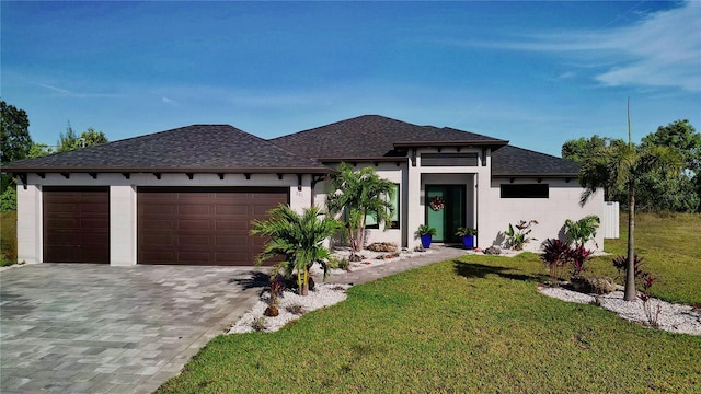 prairie-style home featuring a garage, a front yard, decorative driveway, and a shingled roof