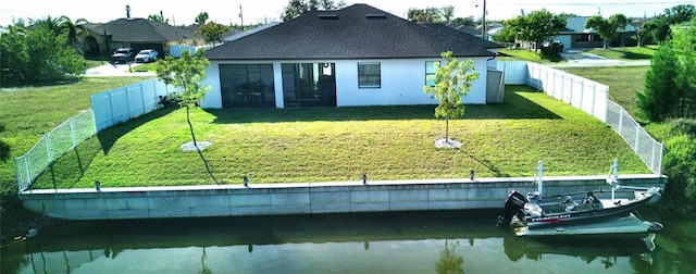 rear view of property featuring a lawn, a water view, and a fenced backyard