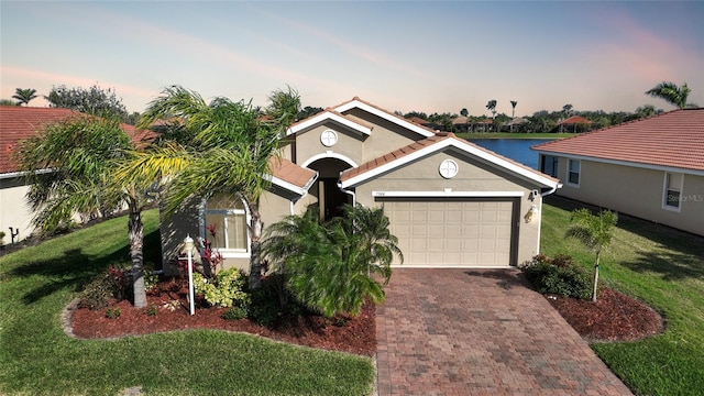 view of front facade featuring a yard, a garage, and a water view