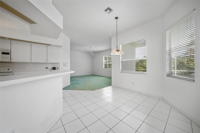 interior space featuring range, light tile patterned floors, white cabinets, pendant lighting, and backsplash